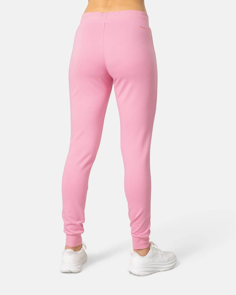 Back view of a woman wearing the bright pink Kari Traa Kari Pant joggers, highlighting the comfortable slim fit.
