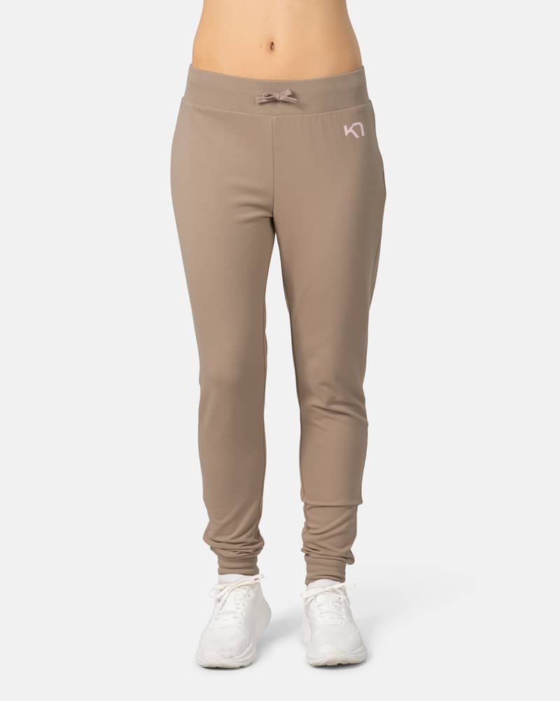 Woman modeling the Kari Traa Kari Pant in mocha, showing its slim-fit style and drawstring waist for lounging.