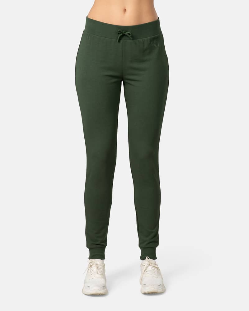 Woman modeling the Kari Traa Kari Pant in dark green, showing its slim-fit style and drawstring waist for lounging.