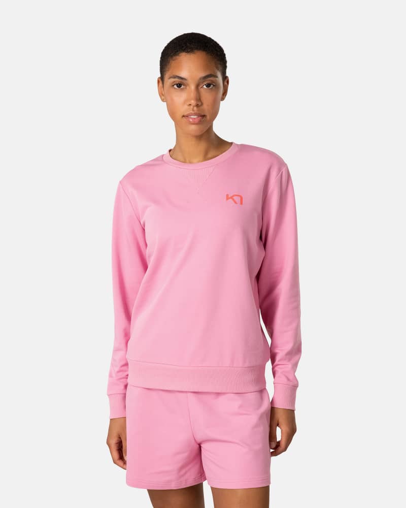 Woman wearing the pink Kari Traa Kari Crew sweater with matching shorts, creating a sporty and comfortable look.