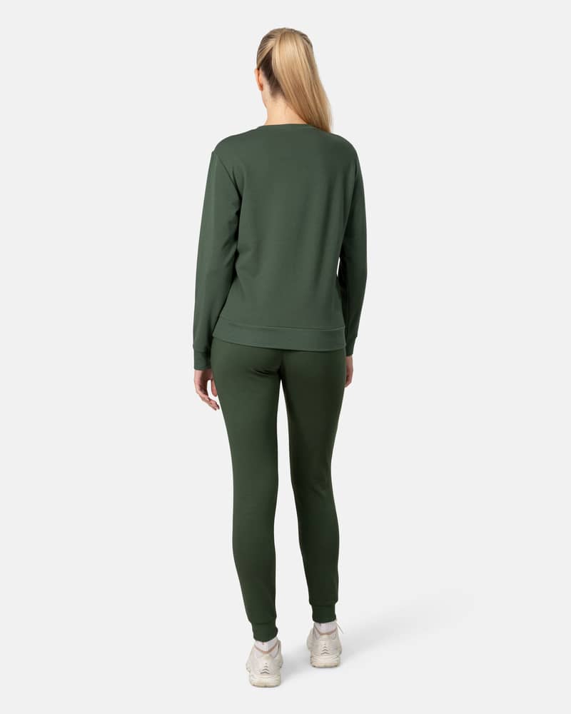 Full back view of a woman wearing the dark green Kari Traa Kari Crew sweater and pants, showing the set's relaxed fit.