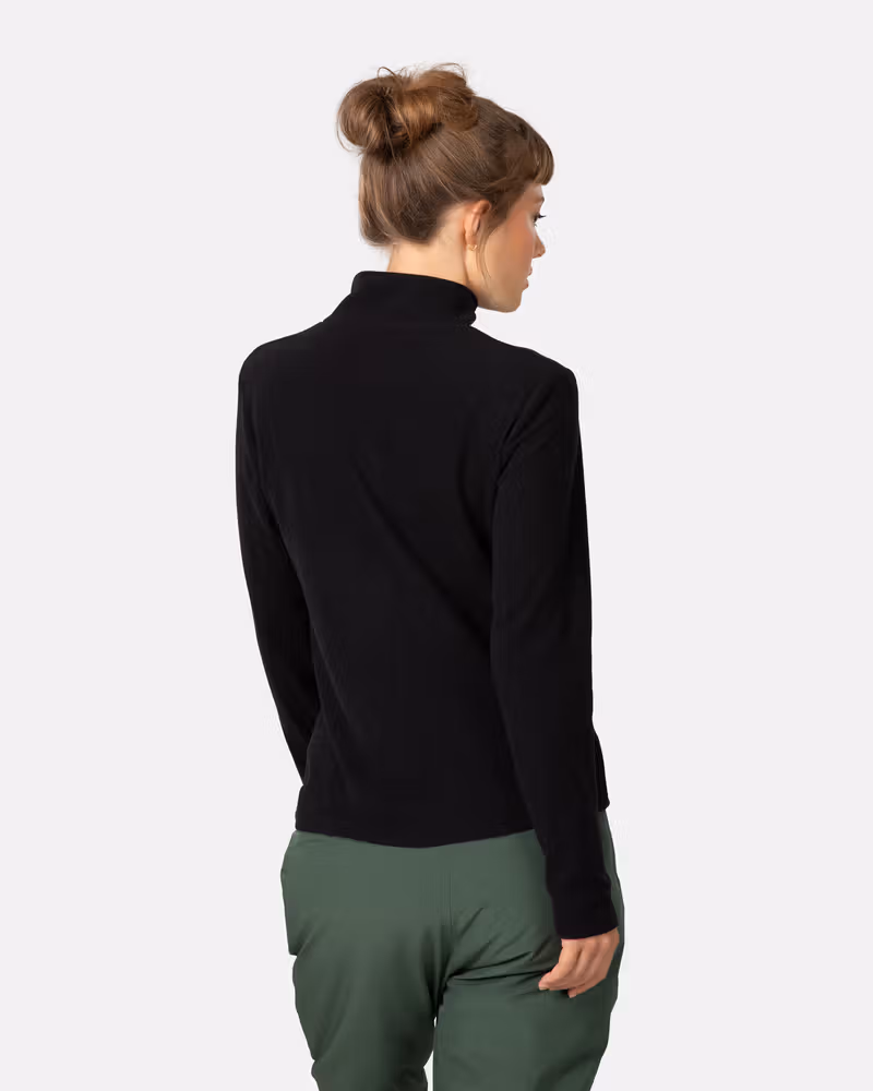 Side view of a woman in the black Kari Traa Kari Full Zip Fleece, showing the high collar and regular fit.
