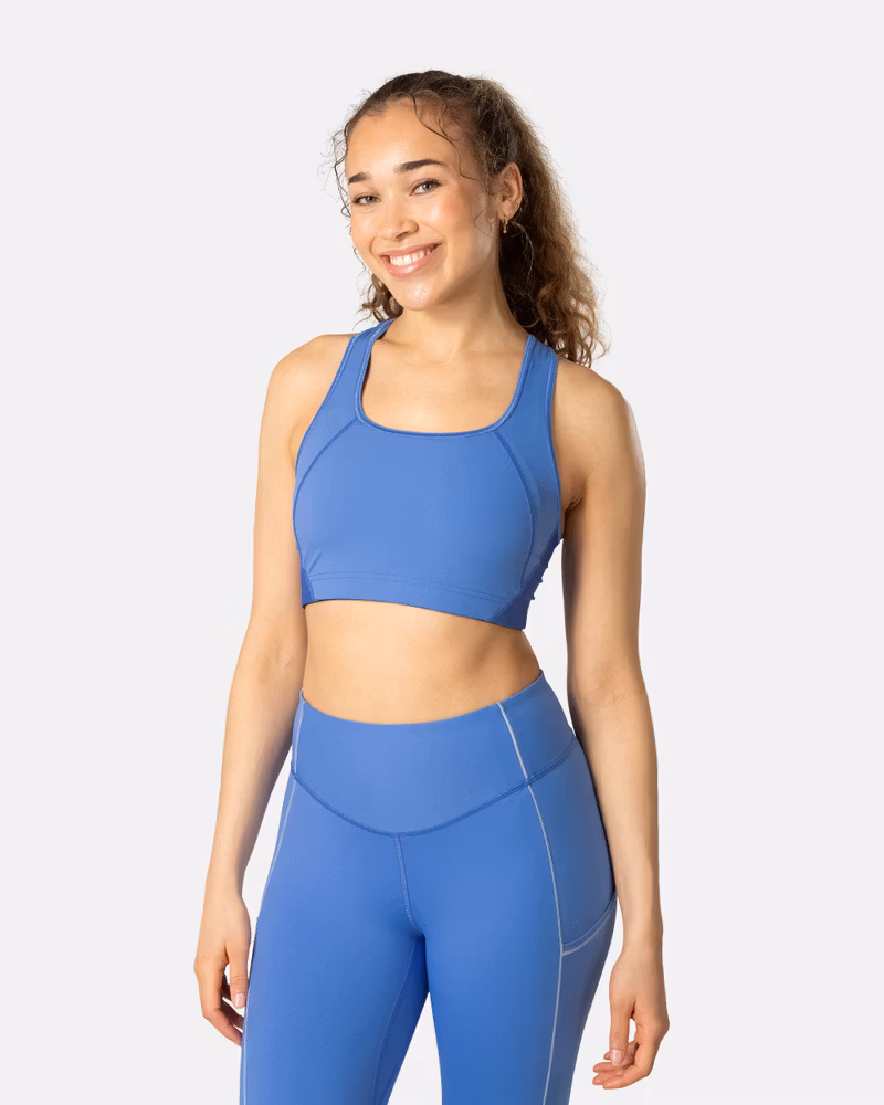 Woman wearing the Kari Traa Trud Sports Bra in blue, a medium-support compression bra for workouts.