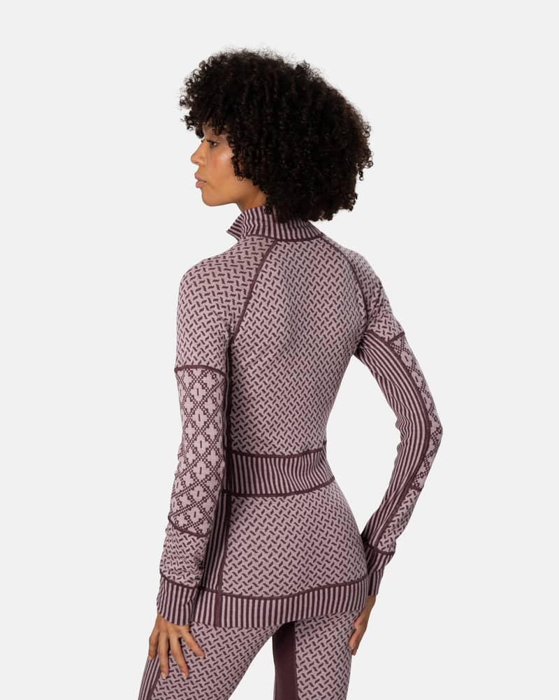 Back view of a woman in the dusty rose Kari Traa Smekker Half Zip, showcasing the various knit patterns.
