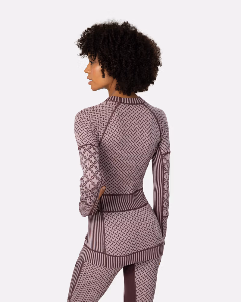 Back view of a woman wearing the dusty rose Kari Traa Smekker Long Sleeve, highlighting how the different knit panels contour the body.