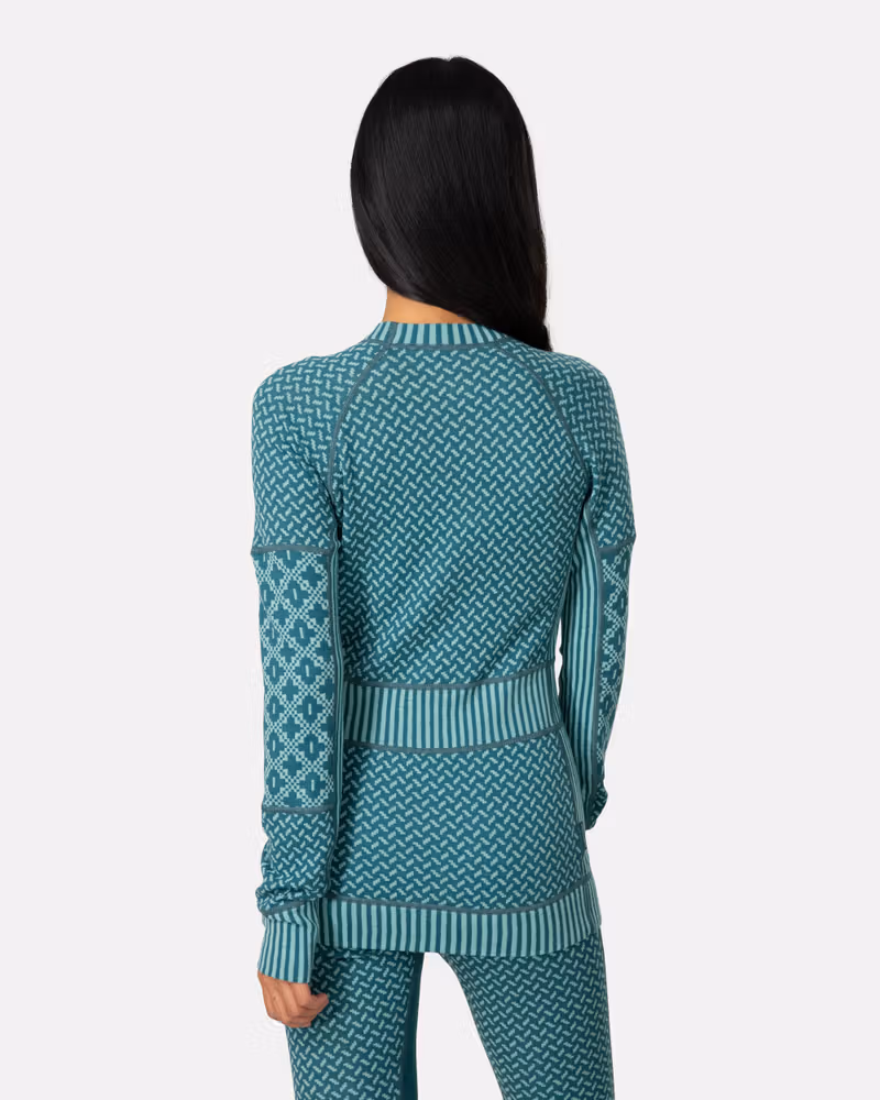Back view of a woman in the teal Kari Traa Smekker Long Sleeve, highlighting the flattering knit patterns.