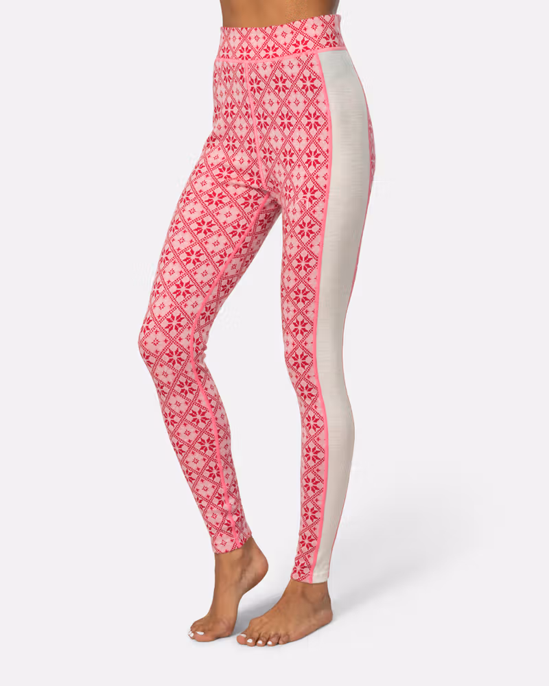 Side view of a woman in pink patterned Kari Traa Rose High Waisted Baselayer Pants, highlighting the slim fit.