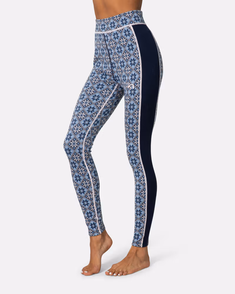 Side view of a woman wearing navy Kari Traa Rose High Waisted Baselayer Pants with a blue floral pattern for warm, stylish layering.