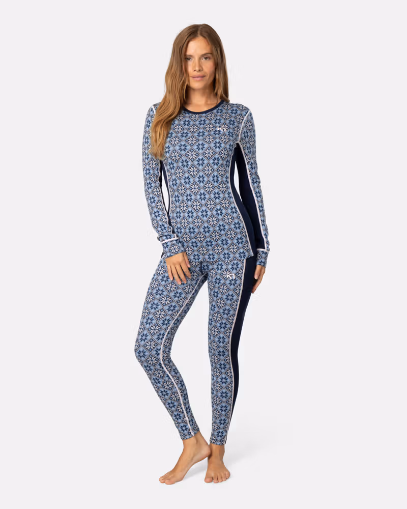 Front view of a woman wearing the navy floral Kari Traa Rose High Waisted Baselayer Pants and matching top for a complete winter set.