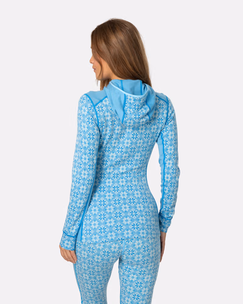 Back view of a woman in the light blue Kari Traa Rose Base Layer Hoodie, highlighting the jacquard knit design.