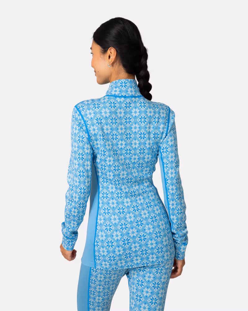 Back view of a woman in the light blue Kari Traa Rose Half Zip top, showcasing the feminine silhouette.