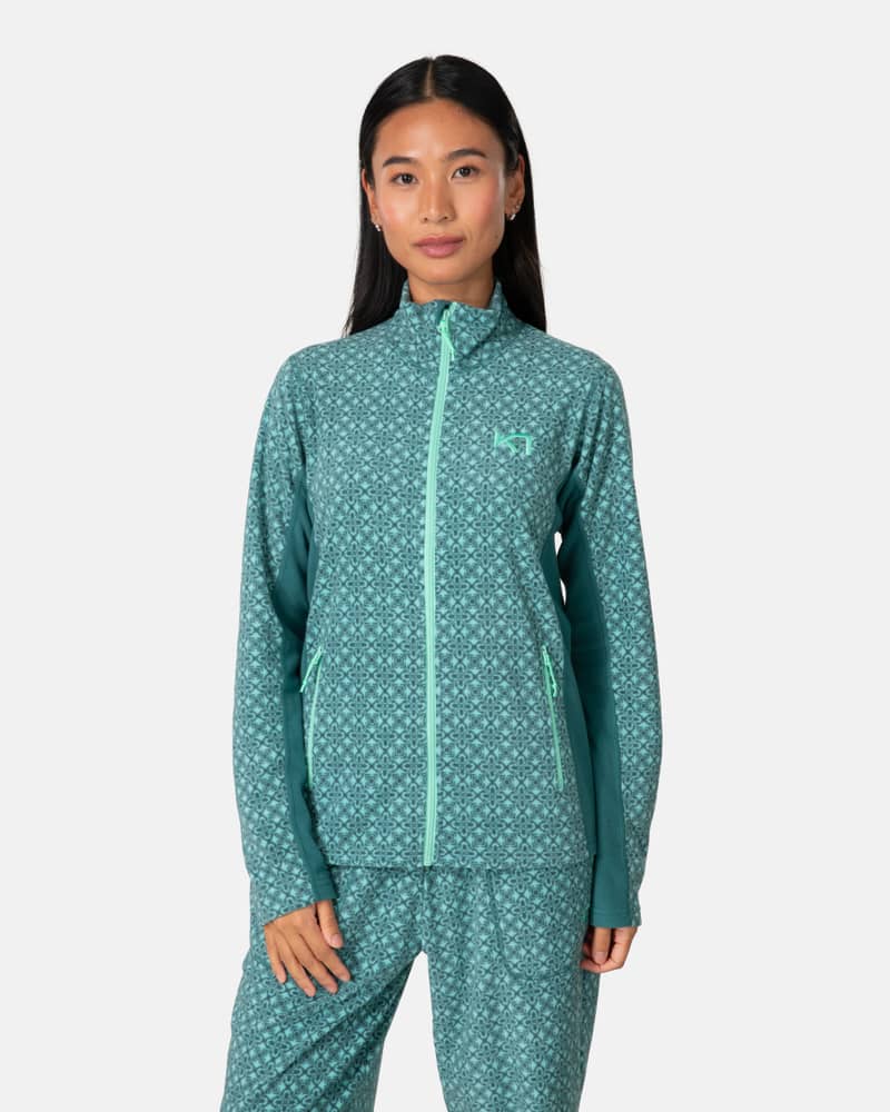 Woman wearing the teal Kari Traa Olga Fleece, a cozy go-to layer with a high collar and zippered pockets.