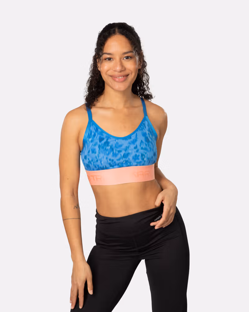 Woman wearing the Kari Traa Frøya Sports Bra in a blue print, a wool-lined bra for light-impact adventures.