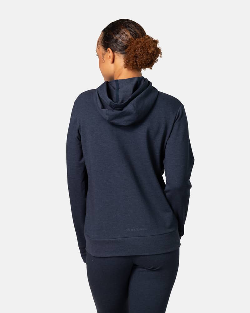 Back view of a woman in the navy blue Kari Traa Kari Hoodie, highlighting the adjustable drawstring hood and relaxed style.