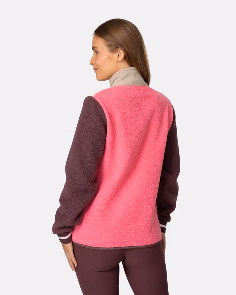 Back view of a woman wearing the color-blocked pink and maroon Kari Traa Røthe Midlayer fleece.