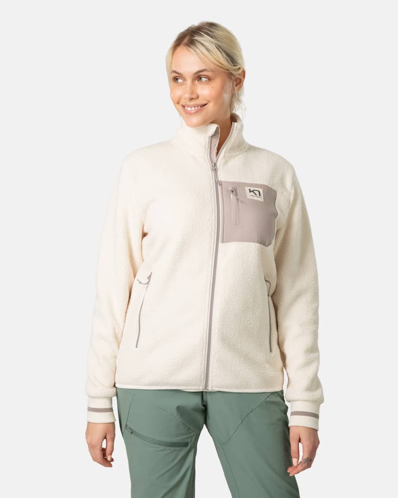 Woman wearing the cream Kari Traa Røthe Midlayer with a grey chest pocket, perfect for layering in cold weather.