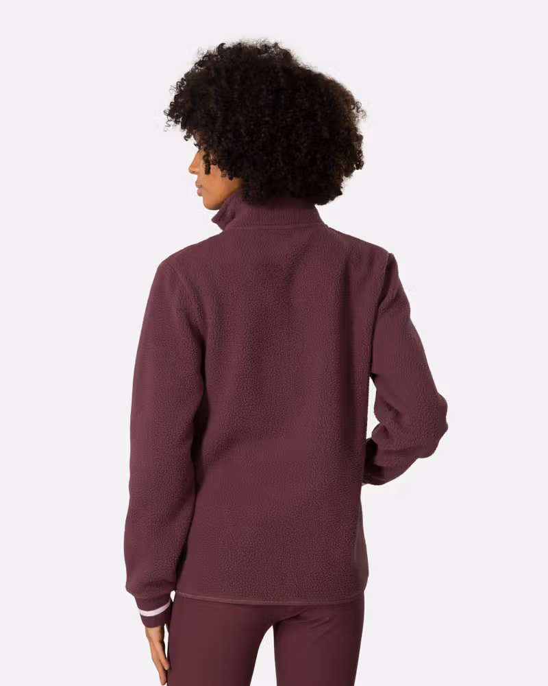 Back view of a woman in the maroon Kari Traa Røthe Midlayer fleece, showing the cozy regular fit.