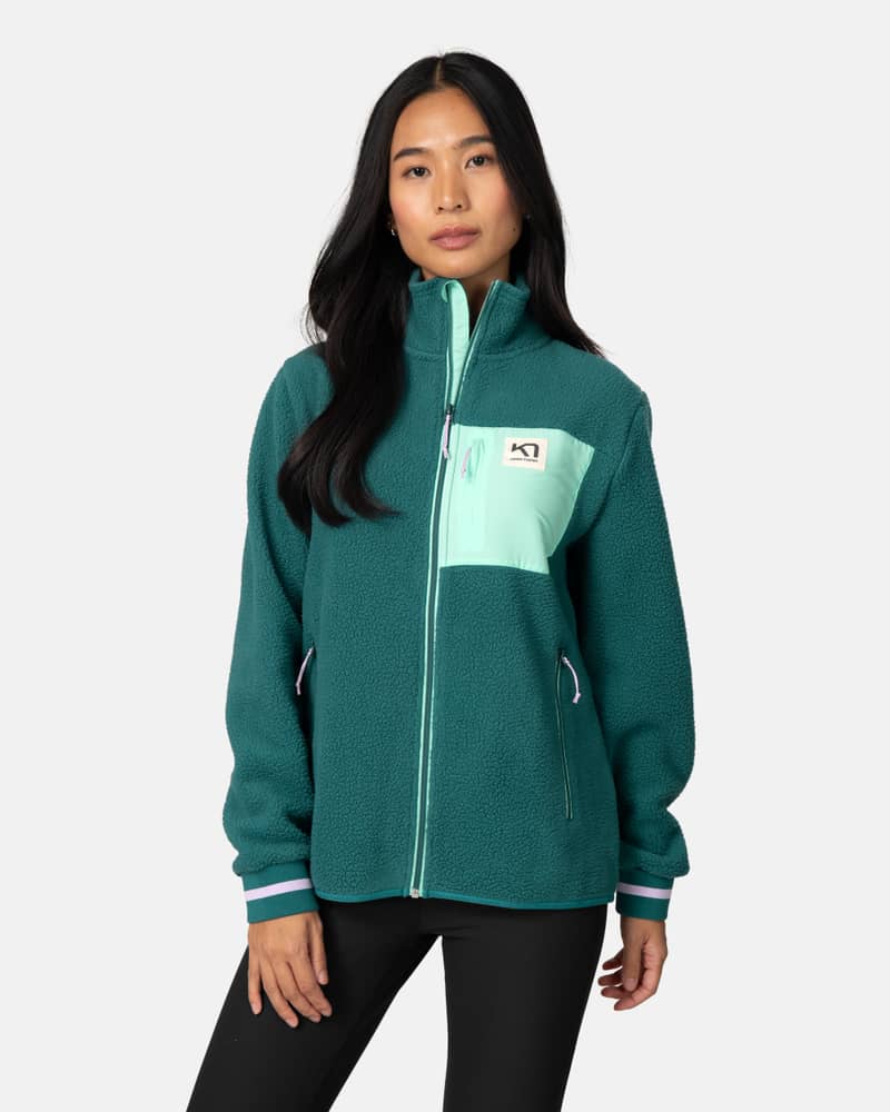Woman wearing the teal Kari Traa Røthe Midlayer fleece, a cozy full-zip jacket with a secure chest pocket.