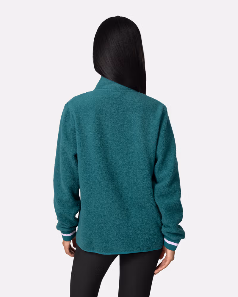 Back view of a woman in the teal Kari Traa Røthe Midlayer, highlighting the warm pile material.