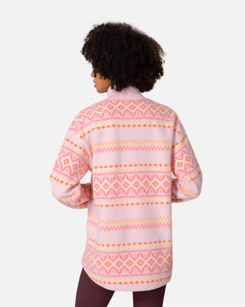 Back view of a woman in the pink striped Kari Traa Ruthie Midlayer, highlighting the relaxed, loose fit.