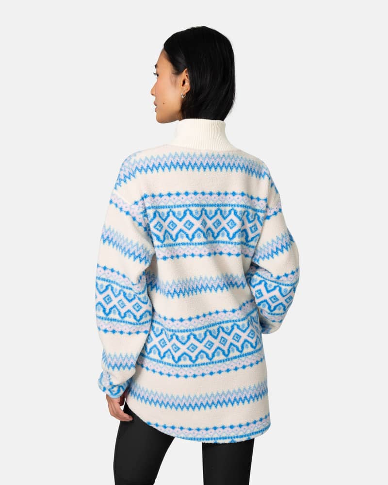 Back view of a woman in the blue striped Kari Traa Ruthie Midlayer, showing the dropped back hem.