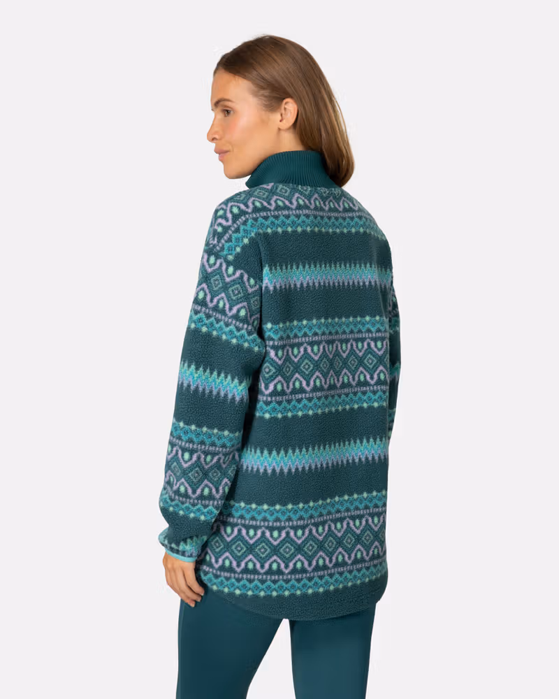 Back view of a woman in the teal striped Kari Traa Ruthie Midlayer, highlighting its loose, comfortable fit.