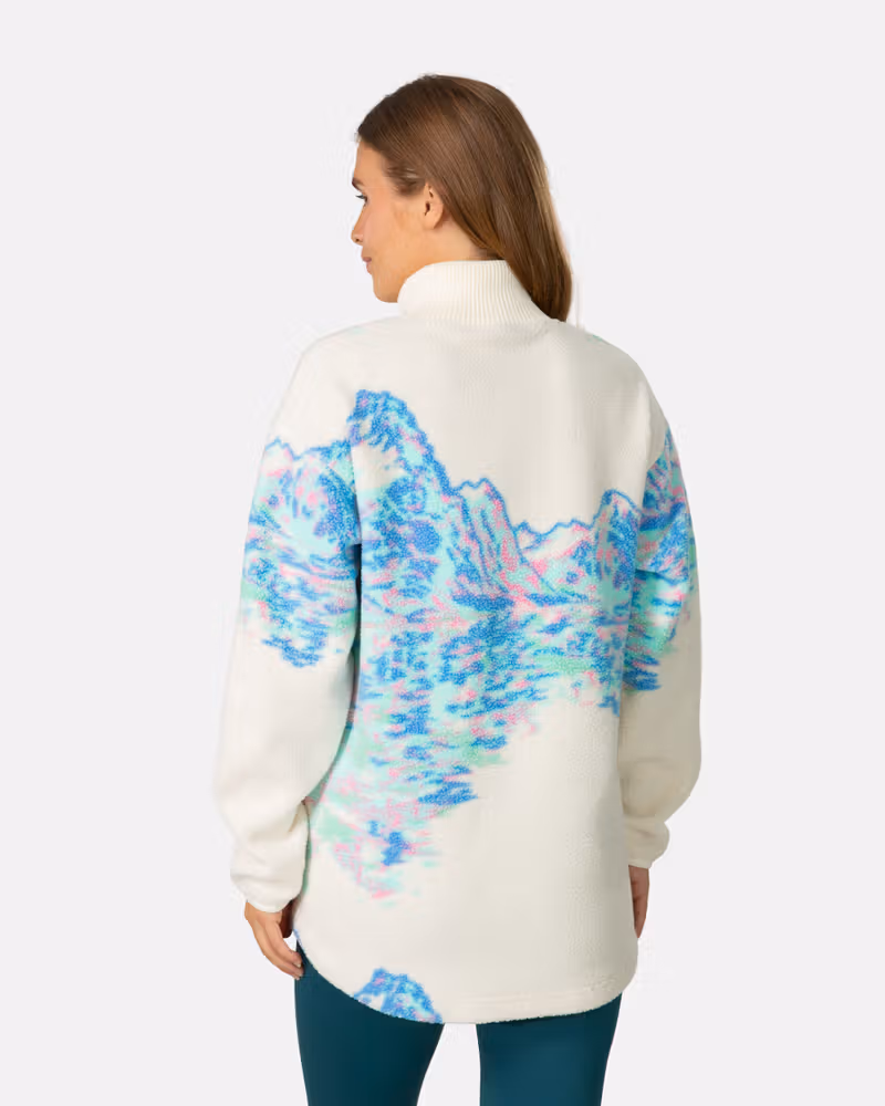 Back of a woman in the Kari Traa Ruthie Midlayer with a blue wave graphic, showing its loose fit and cozy feel.