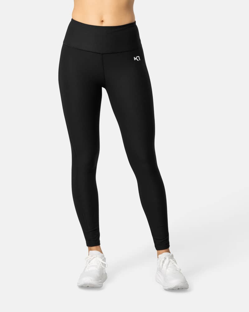 Woman wearing black Kari Traa Nina High Waist Tights, showcasing the slim fit and wide waistband for comfort and coverage.