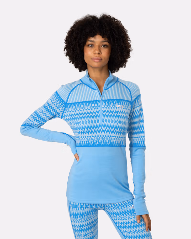 Woman wearing the light blue Kari Traa Silja 2.0 Half Zip, showing the jacquard knit sleeves and zip collar.