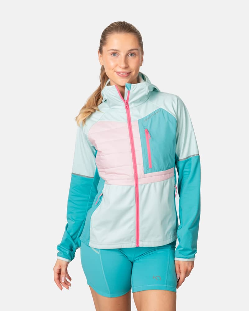Woman wearing the Kari Traa Nia running jacket in teal and pink, featuring a high collar and zippered pockets.