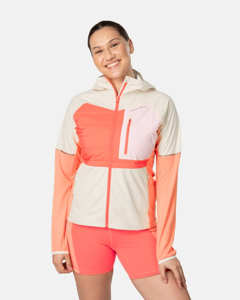 Woman smiling in the Kari Traa Nia Jacket in a coral and beige colorblock, ideal for running and training outdoors.