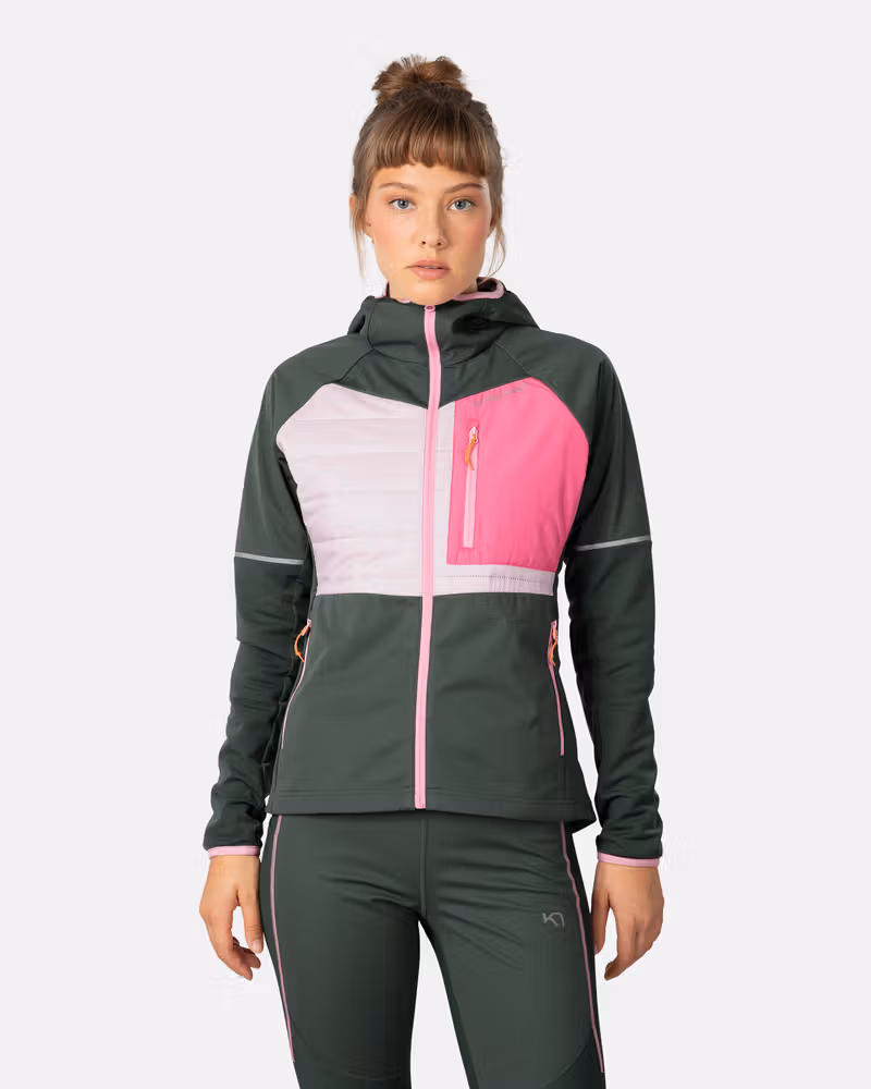 Woman wearing the Kari Traa Nia Jacket in thyme, a sporty green and pink layer for running and outdoor training.