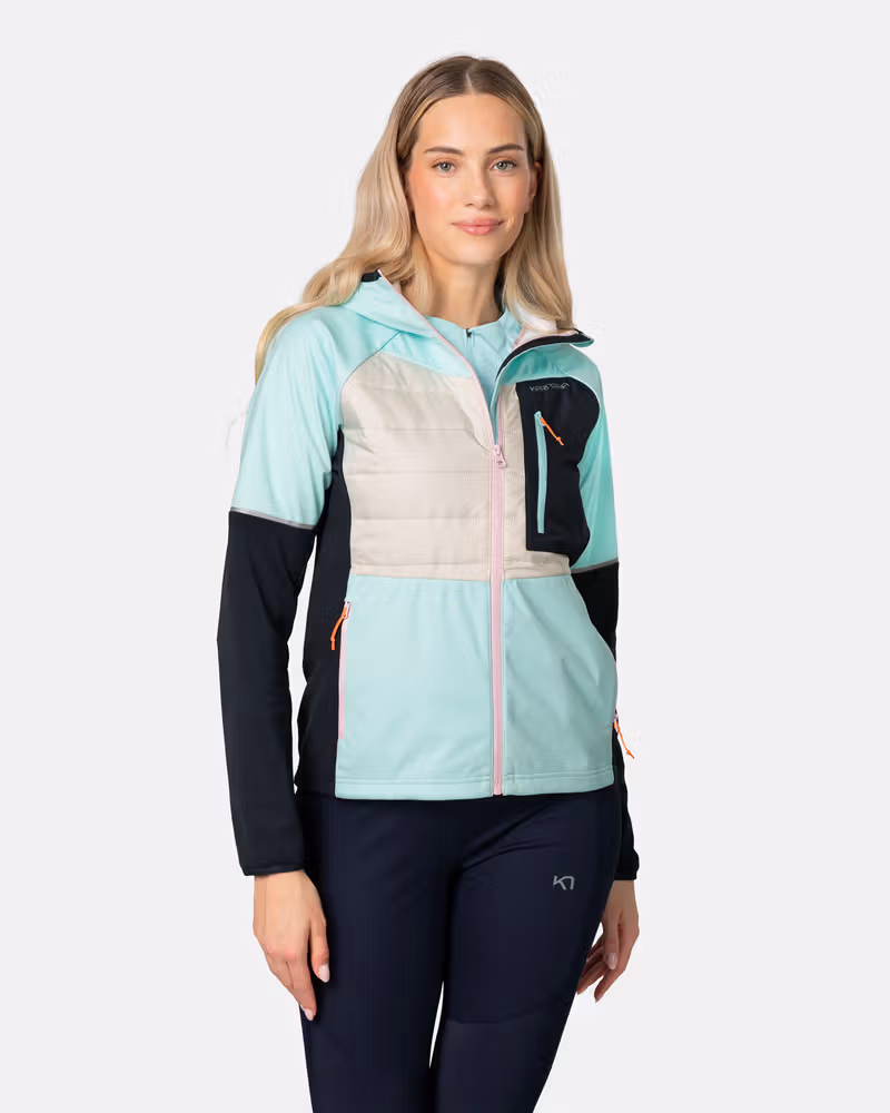 Woman wearing the Kari Traa Nia Jacket in a mint/dark blue combo, featuring a high collar and zippered pockets, perfect for running.