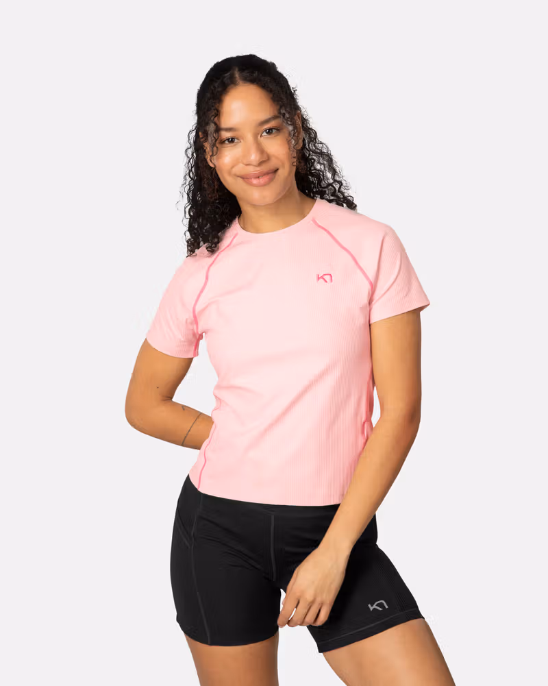 Woman wearing the cotton candy pink Kari Traa Linnea Tee, a performance top with contrast stitching and a slim fit.