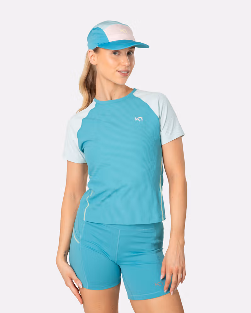 Woman wearing the Kari Traa Linnea Tee in blue lagoon with contrast raglan sleeves, styled for running.