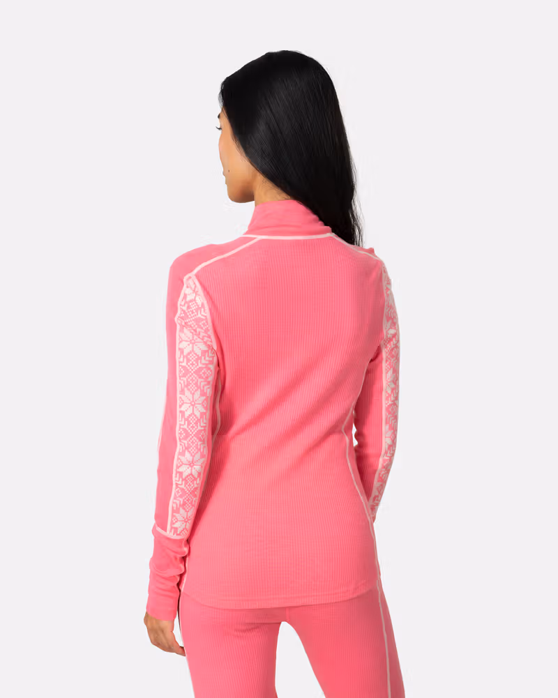 Back view of woman in Kari Traa Anna Half Zip in pink with Nordic print sleeves, merino wool base layer