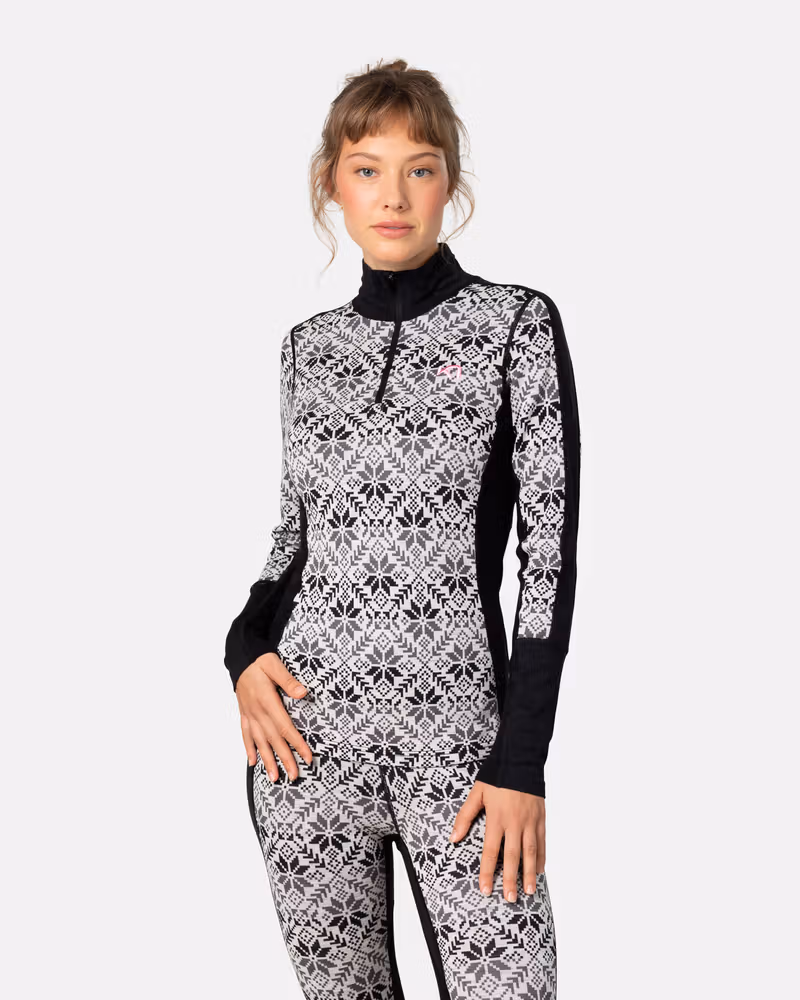 Front view of woman in Kari Traa Anna Half Zip in black with Nordic snowflake print, merino wool base layer