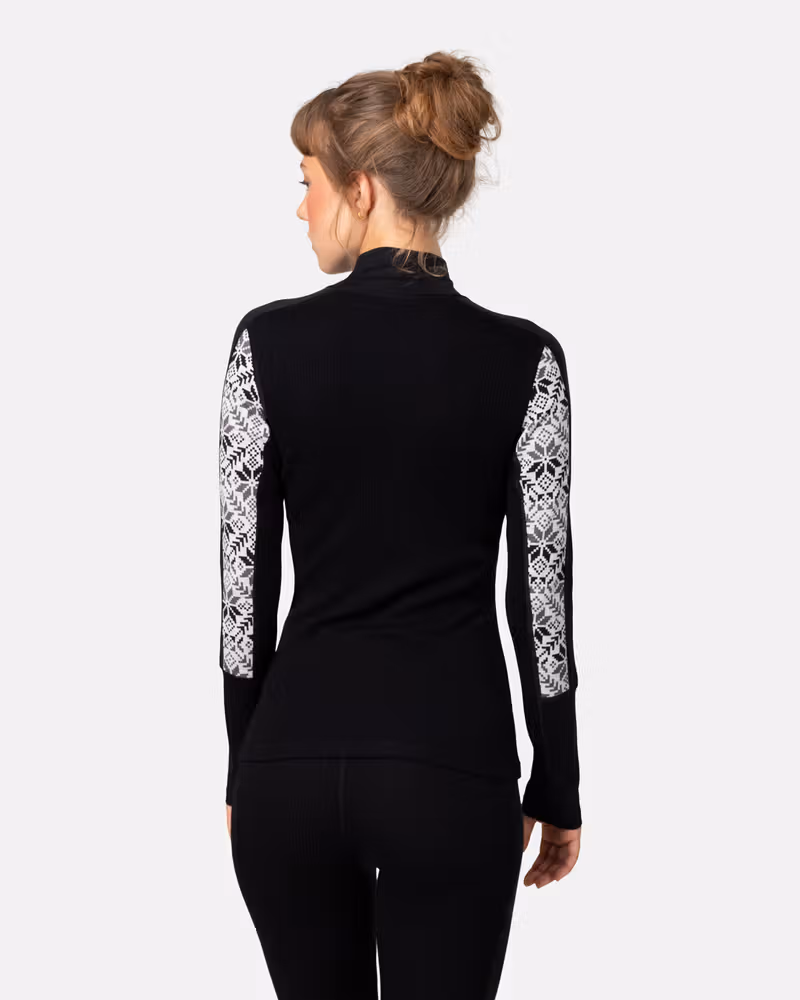 Back view of woman in Kari Traa Anna Half Zip in black, merino wool base layer with white Nordic print sleeves
