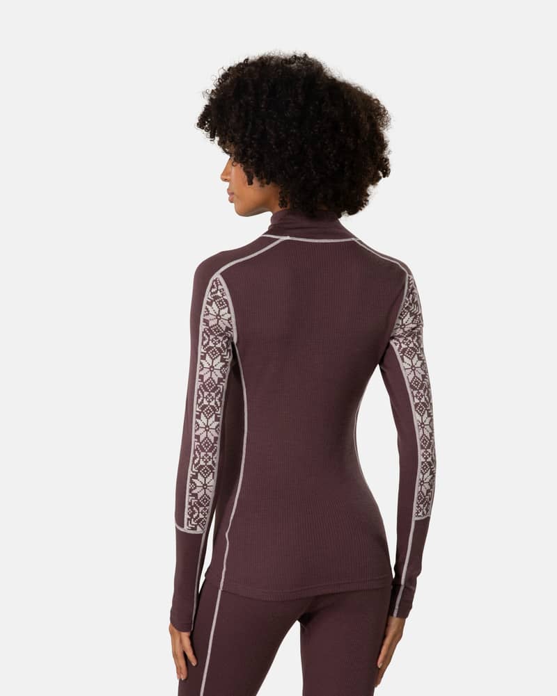 Back view of woman in Kari Traa Anna Half Zip in dark red, merino wool base layer with Nordic print sleeves