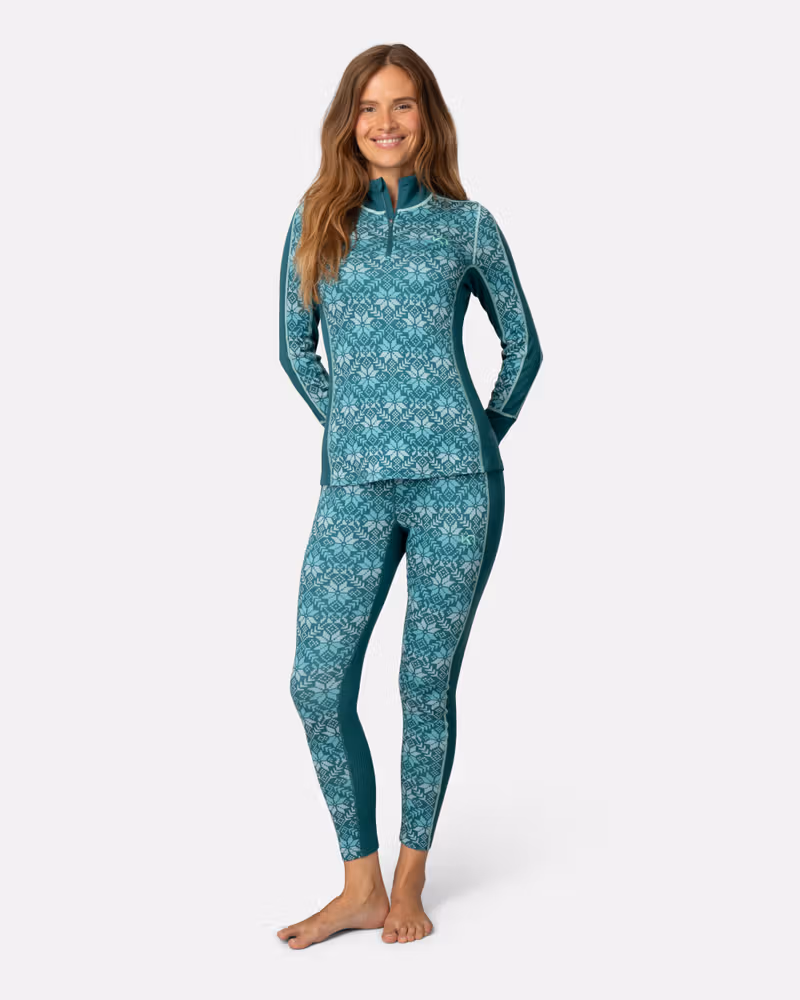 Woman wearing Kari Traa teal Anna Half Zip merino wool base layer with Nordic print, full body shot
