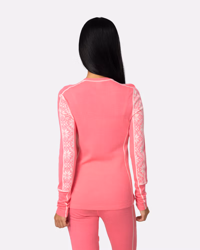 Back view of a woman in the bright pink Kari Traa Anna Long Sleeve, showing the contrast side panels.