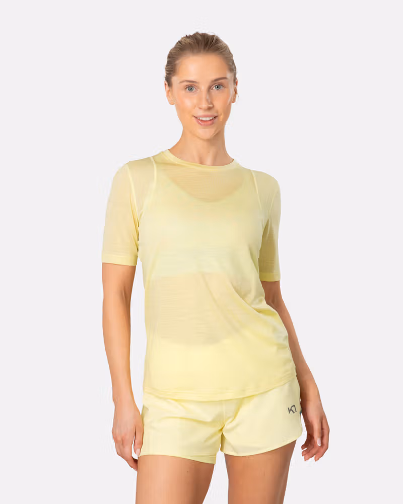 Woman wearing the Kari Traa Embla Wool Tee in yellow, a lightweight and breathable Merino wool blend base layer.