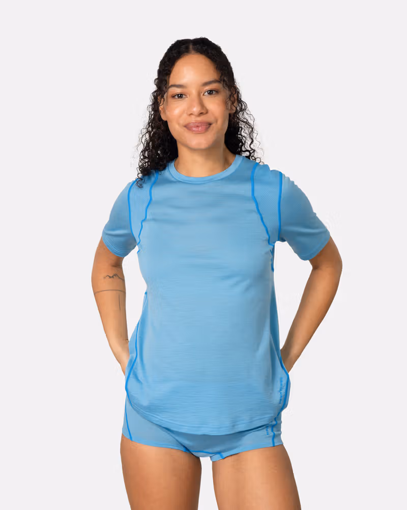 Woman wearing the Kari Traa Embla Wool Tee in blue, a lightweight and breathable Merino wool blend base layer.
