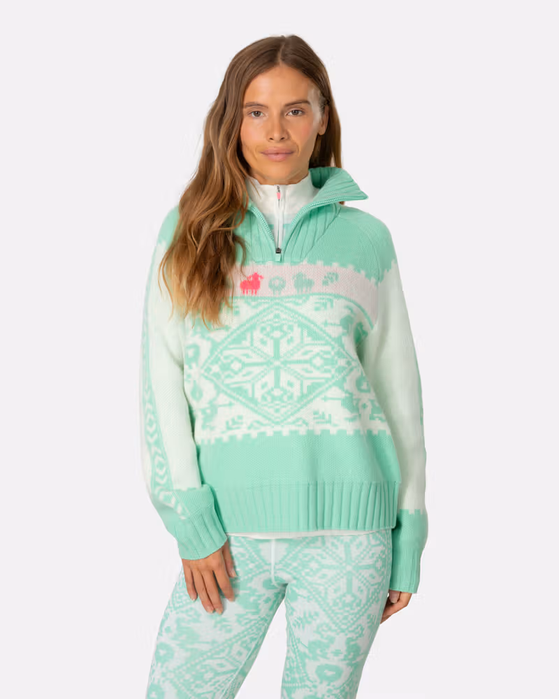 Woman wearing the mint green and white Kari Traa Saga Knit sweater, showing the voluminous sleeves and cozy high collar.