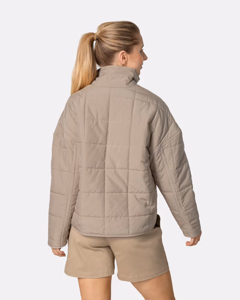 Back view of a woman in the mocha Kari Traa Mina Jacket, showing the loose fit and quilted padding for warmth.