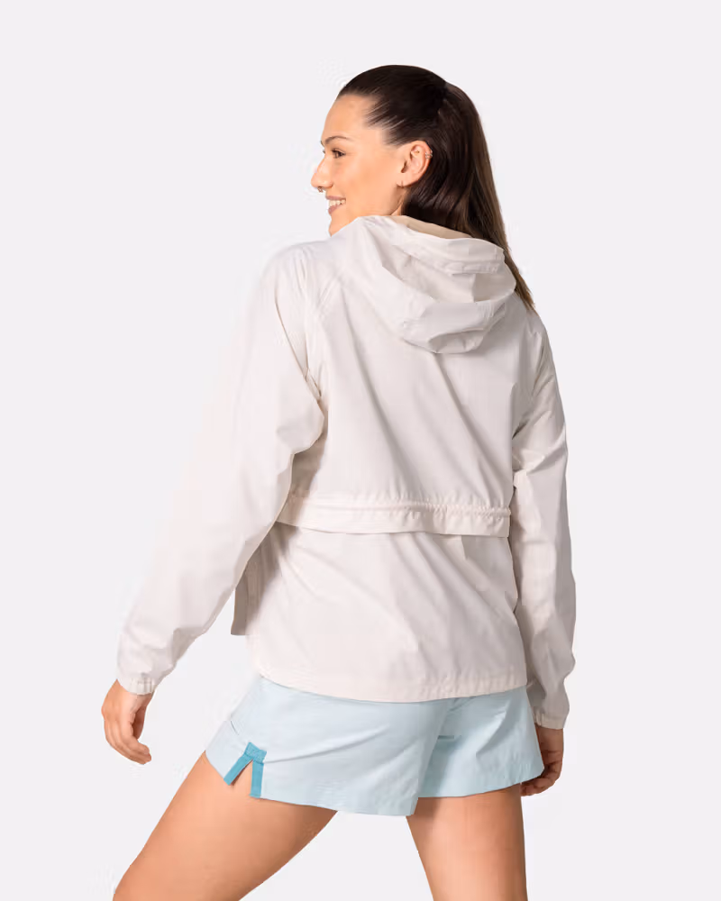 Back view of a woman in the off-white Kari Traa Luna Jacket, showing the fixed hood and adjustable waistband for a custom fit.
