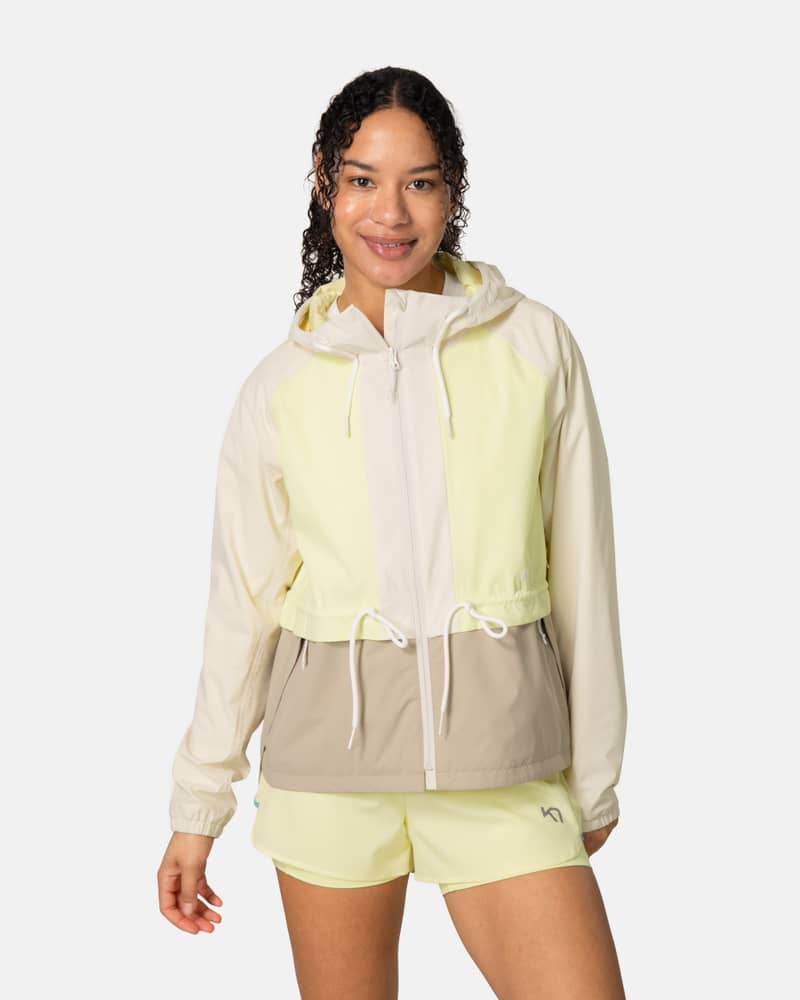 Woman wearing the Kari Traa Luna Jacket in light yellow and tan, a weatherproof layer with an adjustable hood.