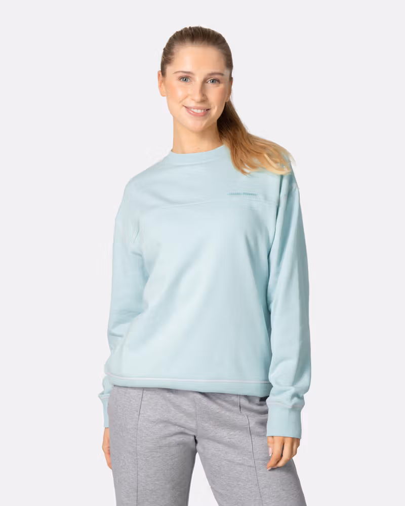 Woman wearing the Kari Traa Synne Crew in light blue, a cozy loungewear sweatshirt with a comfortable loose fit.