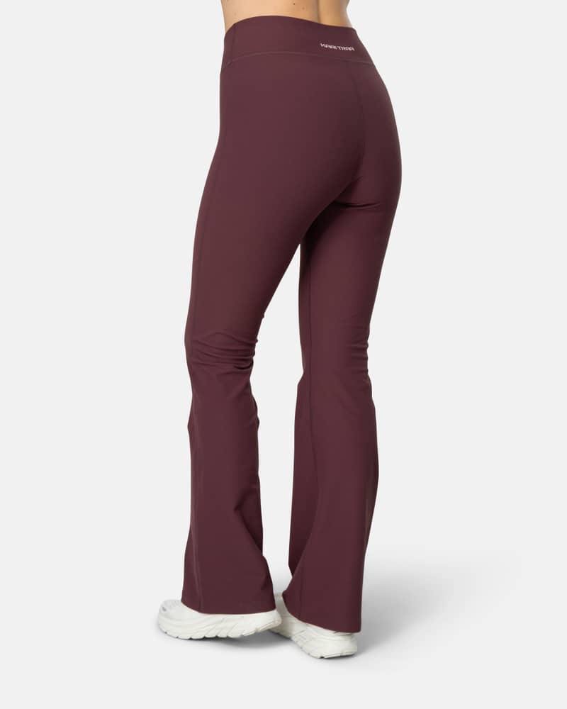 Back view of a woman in maroon Kari Traa Nina Flare Tights, highlighting the wide waistband for comfort and coverage.