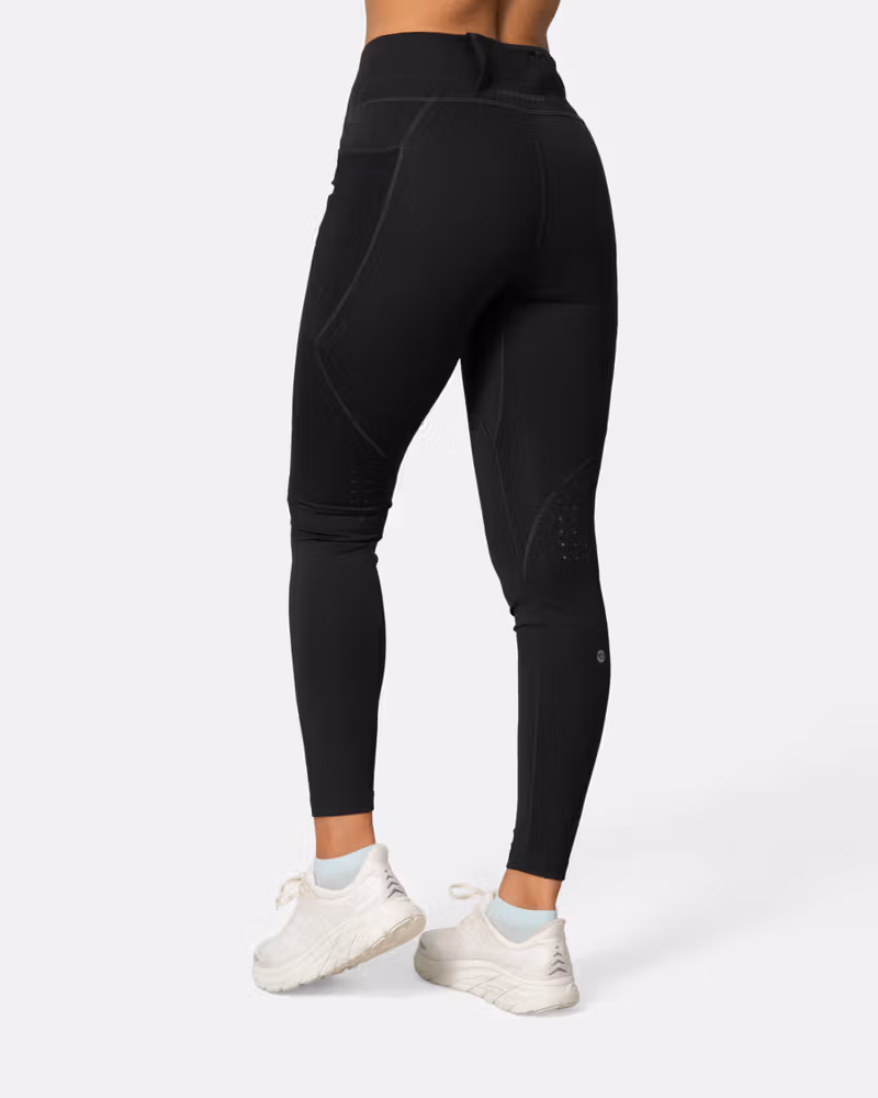 Back-side view of a woman in the black Kari Traa Nia Tights, highlighting the flattering fit and secure back pocket.